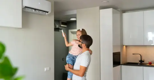 Father carrying her daughter as she turns on the AC
